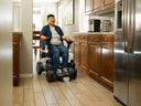 Rider driving a Strutt ev¹ through a home kitchen between the cabinets and the refrigerator