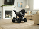 Strutt ev¹ parked on the carpet of a living room beside a sofa and fireplace