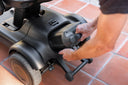 Close-up of hands holding a grip handle at the rear of the Strutt ev¹ base