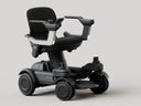 Strutt ev¹ smart power chair, front three-quarter studio view showing the seat, both armrests, footplate and four wheels