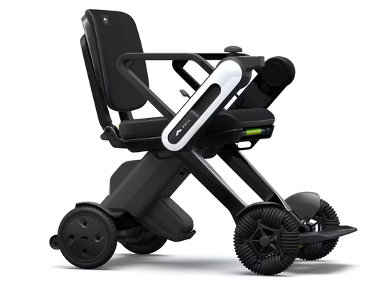 WHILL Model C Lite folding carbon electric wheelchair, side view, showing the carbon fibre X-frame, black seat and backrest, white WHILL arm-mounted controller, and front omni-directional wheels.