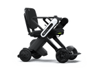 WHILL Model C Lite folding carbon electric wheelchair, three-quarter front view: black seat and backrest with WHILL logo, white arm-mounted controller, carbon fibre X-frame and front omni wheels.